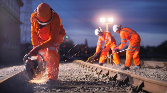Operários realizando manutenção em trilho de trem à noite