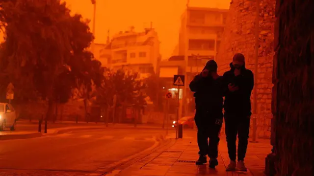 Люди закрывают лица, чтобы защититься от пыли, которая накрыла остров Крит в Греции 1 апреля 2026 года в результате сахарской пыльной бури.
