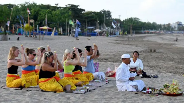 Turis asing berpartisipasi dalam acara ibadah umat Hindu Bali di sebuah pantai di Seminyak, Bali, pada 5 Agustus 2023.