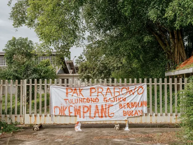 Spanduk permohonan dari para pekerja di gerbang pabrik garmen yang tutup, di Karanganyar, Jawa Tengah, Indonesia pada hari Rabu, 12 Februari 2025. Indonesia kehilangan sekitar seperempat juta pekerjaan di industri tekstil dan pakaian jadi selama dua tahun terakhir, menurut Asosiasi Produsen Serat dan Benang Filamen Indonesia.
