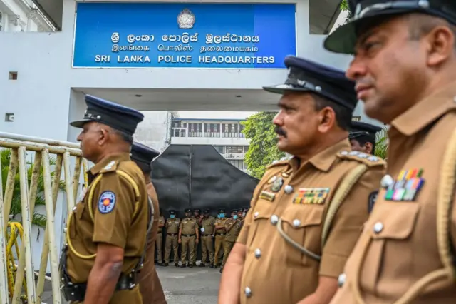 පොලිස් මුලස්ථානය ඉදිරිපිට රැඳී සිටින පොලිස් නිලධාරීන් පිරිසක් 