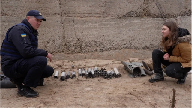 Fundi wa kikosi cha mabomu Oleksandr Remenets akimuonyesha ripota wa BBC Viktoriia Zhuhan mkusanyiko wa silaha huko Chernihiv.