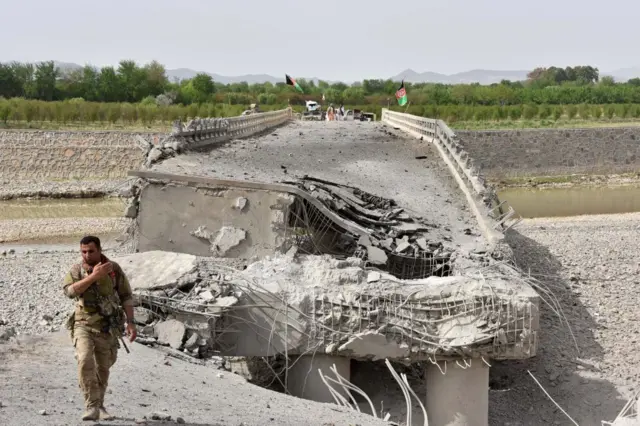 نمای از تخریب یک پل که یک نظامی در کنار آن مسلح دیده میشود
