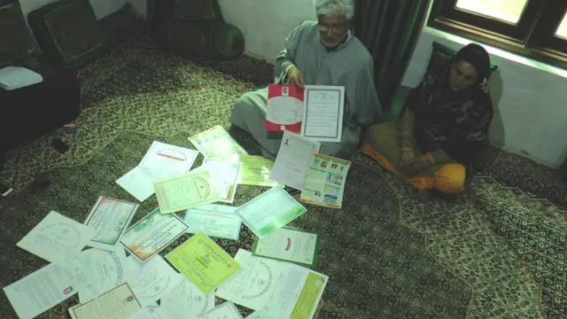 डॉ. बारी के माता-पिता अपने बेटे के डिग्री, अवार्ड्स और सर्टिफिकेट दिखाते हुए