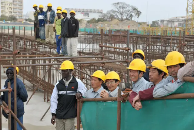 Trabalhadores chineses e senegaleses no local do semi-construído Teatro Nacional, no Senegal