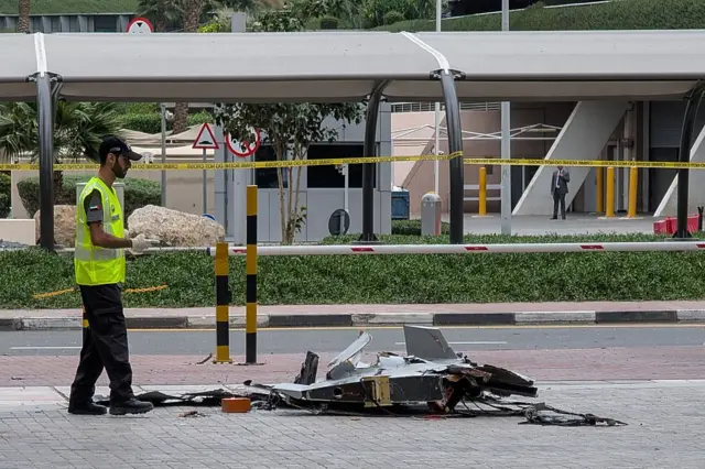 Полицейский инспектирует обломки дрона, упавшего в бизнес-районе Дубая 12 мая 2026