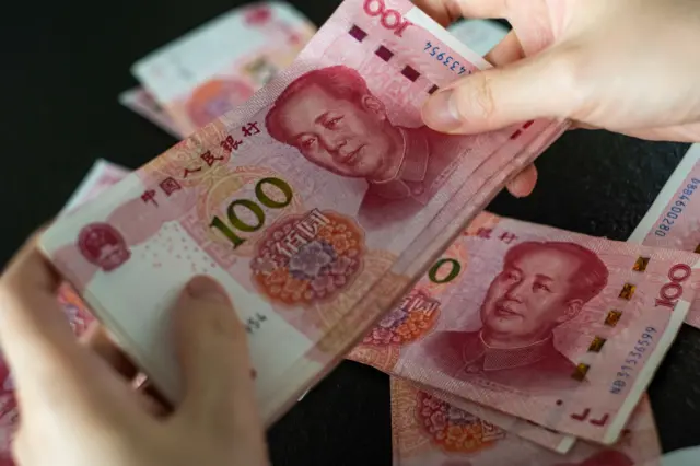 Des mains tenant des billets de Yuan chinois.