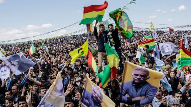 Masyarakat mengibarkan bendera Kurdi dan bendera bergambar pemimpin Kurdi yang dipenjara, Abdullah Ocalan, ketika mereka merayakan Newroz di tahun 2015