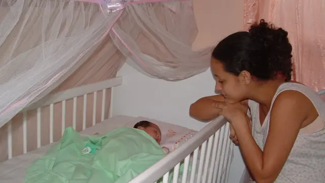 Luana observa a filha recém-nascida que está no berço