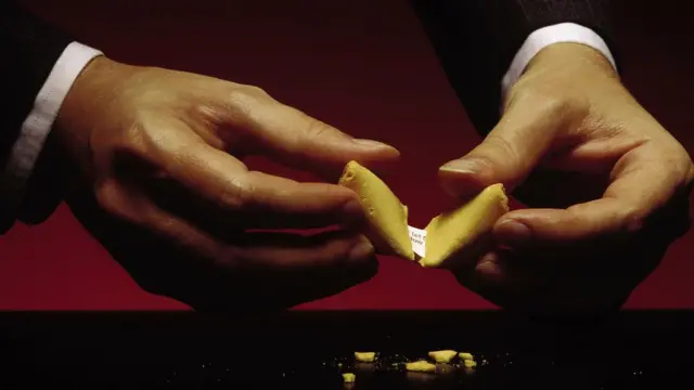 Manos partiendo una galleta de la suerte china