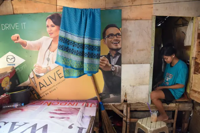 Seorang anak memainkan gawai di rumahnya yang berdiri di bantaran Kali Ciliwung, Tanah Abang, Jakarta, Jumat (25/07/2025).