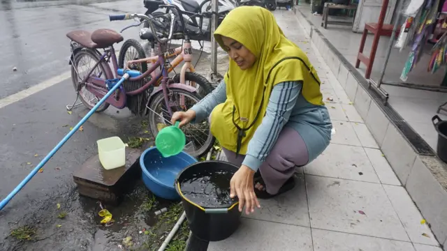 Seorang perempuan di Aceh sedang menyendok air.