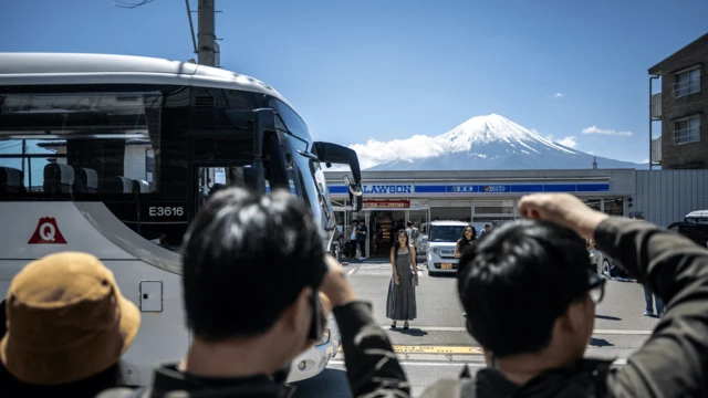 2024年5月3日，游客在便利商店对面的街道上拍摄富士山。