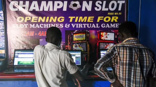 Men bet on the matches of the 2018 FIFA World Cup before the opening match at a sports betting shop in Kampala, Uganda, on June 14, 2018