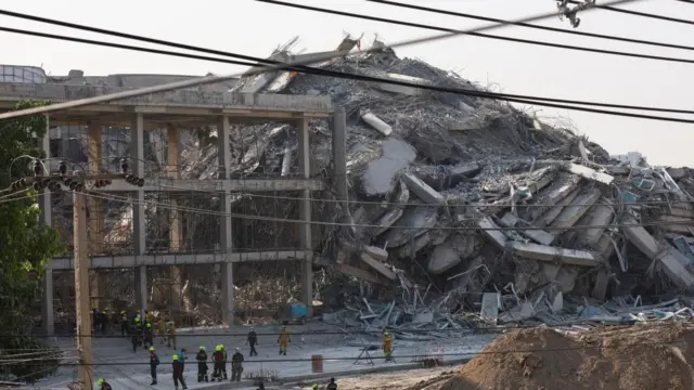 Le personnel de secours se tient près d'un immeuble de Bangkok qui s'est effondré à la suite d'un fort tremblement de terre