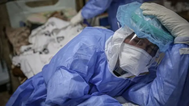 طبيب يرتدي بزة عازلة ويضع يده على رأسه في إحدى المستشفيات في محافظة إدلب مع تفاقم وضع كورونا في البلاد