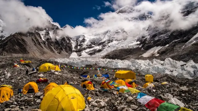خيام نصبت في معسكر قاعدة إيفرست على نهر خومبو الجليدي ، جبل إيفرست ، خلفها غيوم موسمية.