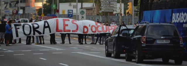 バルセロナ中心部の道路を封鎖するデモ参加者ら。垂れ幕には「占領勢力は出ていけ！」と書かれている（3日）