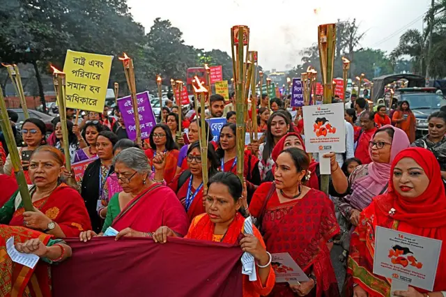 Kırmızı giyinmiş kadınlar ellerinde pankartlarla yürüyor