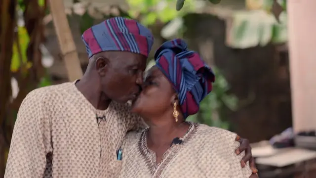 Amos ati Maria Adejinmi wọ leesi alawọ goolu iru kannaa, we gele ati fila aso oke alawọ buluu ati waini, wọn dijọ fi ẹnu ko ara wọn lẹnu.