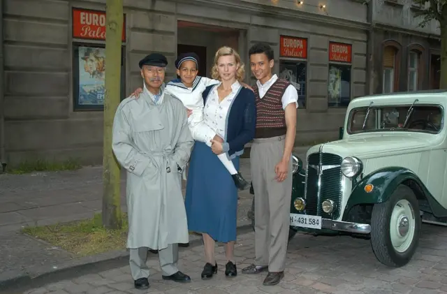 Hans-Jürgen Massaquoi, Lukas Hansen (ou Luka Kumi, 2e à partir de la gauche), Veronica Ferres, Thando Walbaum (à droite) – l'auteur et les acteurs du téléfilm en deux parties diffusé sur ZDF « Neger, Neger, Schornsteinfeger »