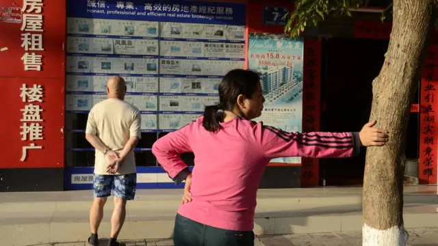 TO GO WITH China-economy-property-Hainan,FEATURE by Tom Hancock This picture taken on January 19, 2013 shows a man (L) checking information posted at the front of a property estate agency at the seaside city of Sanya, in China's southern Hainan province.