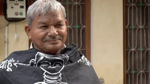 Lal Bihari Mritak sentado em entrevista, em área externa