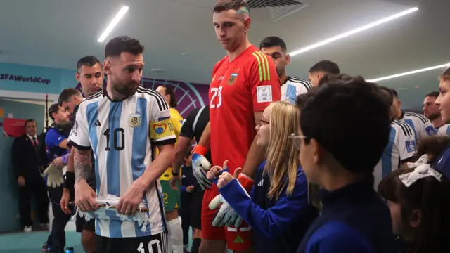 Lionel Messi fala com crianças enquanto se preparam para sair do túnel