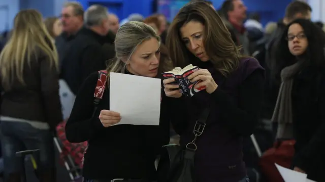 Dos mujeres buscan en un diccionario.