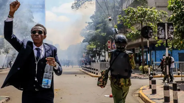 متظاهر يير إلى جوار جندي بالقرب من مبنى البرلمان في العاصمة الكينية نيروبي