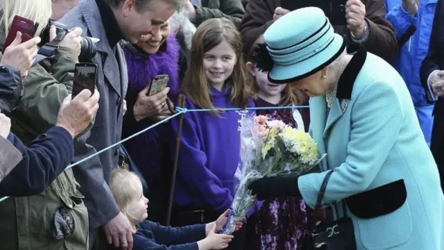 ब्रिटेन की महारानी एलिज़ाबेथ द्वितीय अपने राज के 65 साल पूरे करने के मौके पर लोगों से फूलों के गुच्छे स्वीकार करती हुईं.