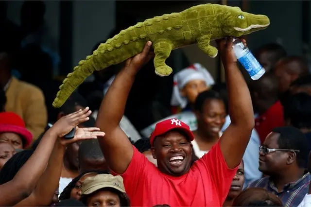 رجل يحمل صورة تمساح للترحيب بالرئيس إيمرسون منانغاغوا المعروف باسم "التمساح" بسبب سمعته كسياسي داهية.