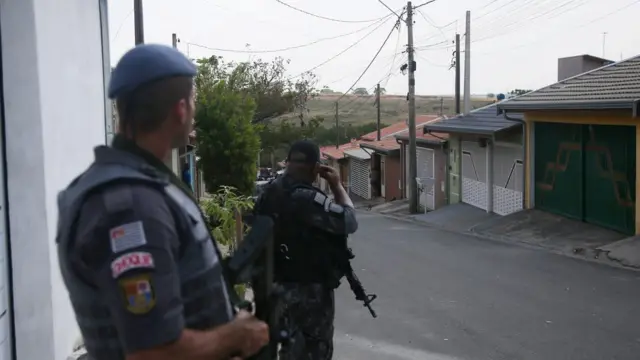 Dois policiais armados fazem patrulhasign in vamos bet sign uprua com casas