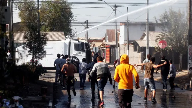 Un carro lanza aguas suelta un fuerte chorro en la calle.