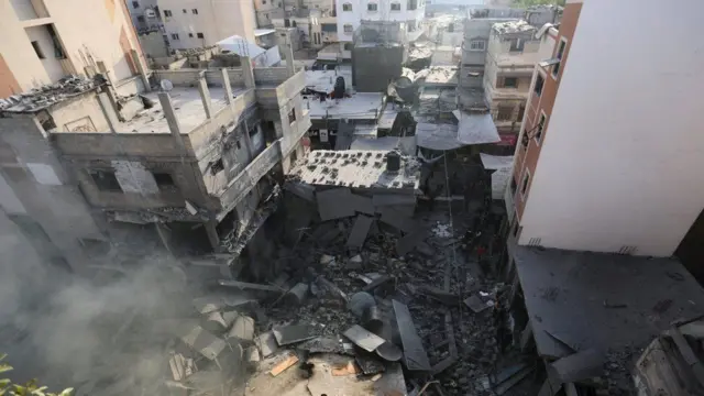 खान यूनिसमा एउटा भवनको भग्नावशेष र त्यहाँबाट निस्किरहेको धुँवा