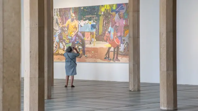 Une femme regarde tableau de Alioune Diagne