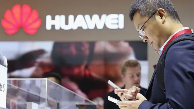 Un hombre viendo a un teléfono de Huawei.