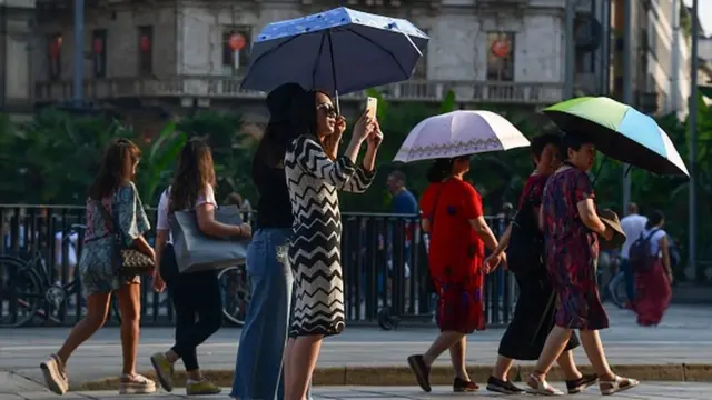 Milan şəhərində Günəşin şüalarından çətir altında gizlənən turistləri görmək olar