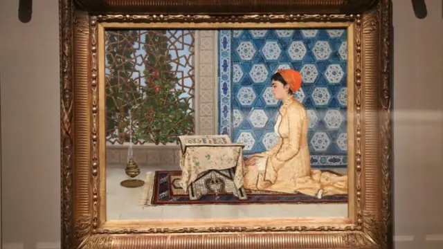 Osman Hamdi Bey'in Genç Kadın Okurken adlı eseri bir camın arkasında duvarda asılı bir şekilde