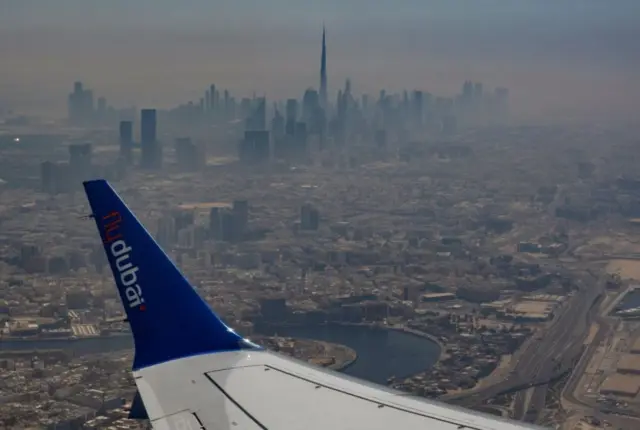 مشهد جوي لأفق دبي يظهر فيه جناح طائرة، وبرج خليفة كما يُرى من طائرة