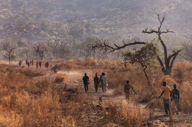 Une savane traversée par un sentier sur lequel marchent des gens