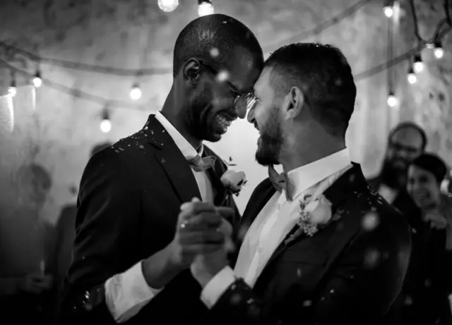 Una pareja de hombres bailan sonrientes en su boda.