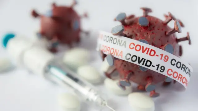 El virus junto a una inyección.