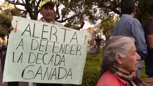 Hombre con cartel que dice: "A defender la década ganada".