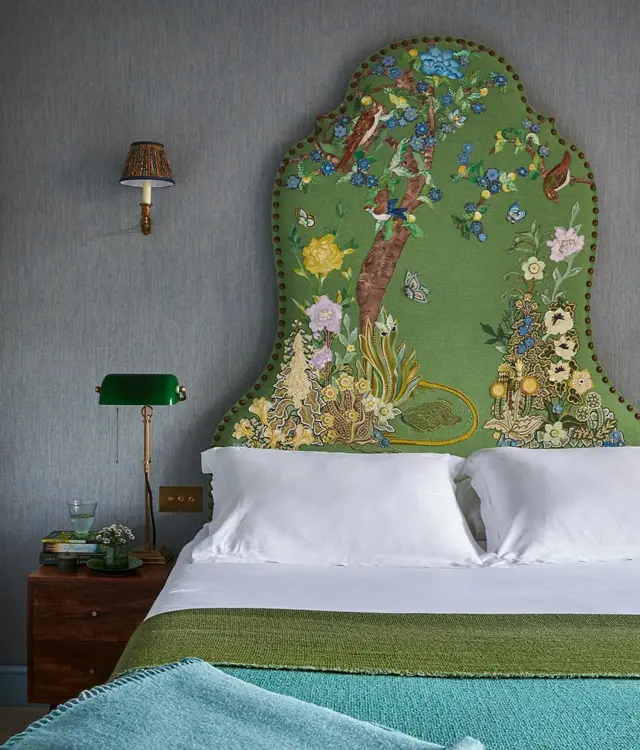 Cama com cabeceira verde e desenhos que lembram natureza