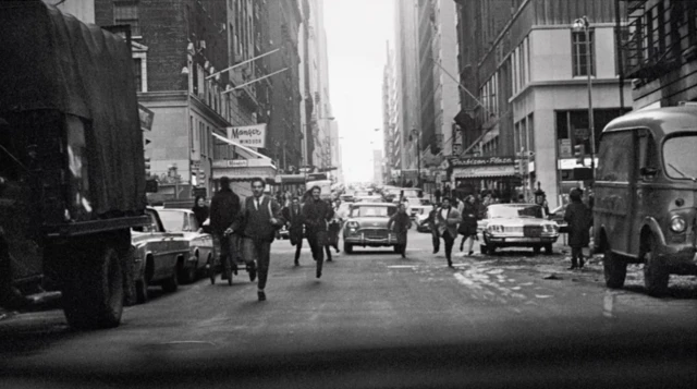 Kerumunan orang mengejar The Beatles di sebuah jalanan kota New York
