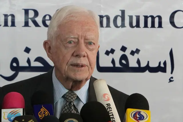 Jimmy Carter mikrofonların önünde. 