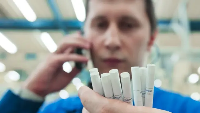 Работник табачной фабрики держит в руке сигареты