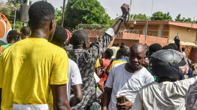 A large crowd of men protesting outside the French embassy in Niamey