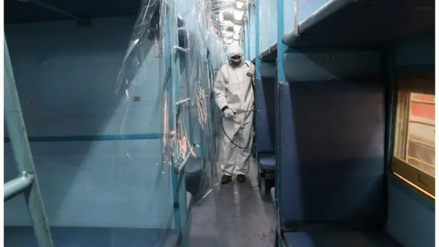 Un travailleur avec son équipement de protection à l'intérieur d'un wagon de train transformé en salle d'isolement pour les patients atteints de COVID-19 près de Kolkata, en Inde